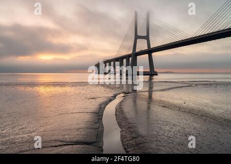 Arrière-plan avec lever de soleil coloré sur le pont de Lisbonne. Le pont Vasco da Gama est un point de repère et l'un des plus longs ponts du monde. réseau local urbain Banque D'Images