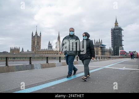 WESTMINSTER LONDRES, ROYAUME-UNI 23 MARS 2021. Des piétons portant des masques protecteurs marchent sur un pont de Westminster tranquille. Aujourd'hui marque l'anniversaire du premier confinement du coronavirus lorsque le gouvernement a demandé aux gens de dire à la maison, de sauver des vies et de protéger le NHS qui sera commémoré dans une journée nationale de réflexion avec un silence d'une minute pour se souvenir des 126,000 victimes qui sont mortes dans la pandémie de Covid. Credit amer ghazzal/Alamy Live News Banque D'Images