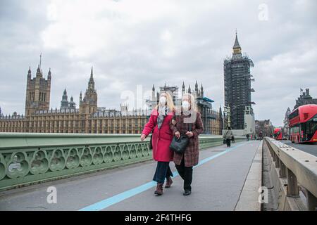 WESTMINSTER LONDRES, ROYAUME-UNI 23 MARS 2021. Des piétons portant des masques protecteurs marchent sur un pont de Westminster tranquille. Aujourd'hui marque l'anniversaire du premier confinement du coronavirus lorsque le gouvernement a demandé aux gens de dire à la maison, de sauver des vies et de protéger le NHS qui sera commémoré dans une journée nationale de réflexion avec un silence d'une minute pour se souvenir des 126,000 victimes qui sont mortes dans la pandémie de Covid. Credit amer ghazzal/Alamy Live News Banque D'Images