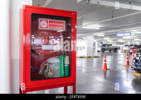 Boîte de dévidoir de tuyau d'incendie dans le coin du parking., la lettre de langue thaï blanc au milieu de la boîte rouge signifie ENROULEUR DE TUYAU D'INCENDIE. Banque D'Images