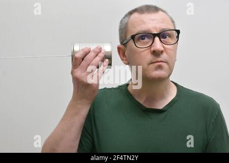 Portrait d'UN homme utilisant et écoutant UNE boîte de étain Téléphone Banque D'Images