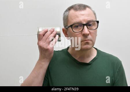 Portrait d'UN homme utilisant et écoutant UNE boîte de étain Téléphone Banque D'Images