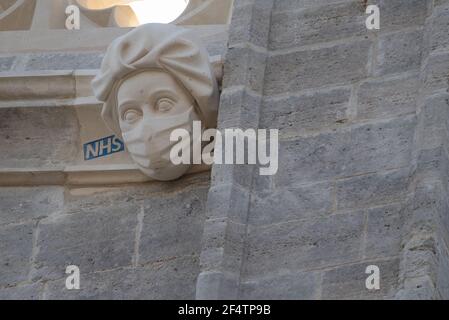 Sculpture d'un travailleur du NHS portant un masque sur le côté du Prieuré de Christchurch à Dorset pendant le troisième confinement national de l'Angleterre pour freiner la propagation du coronavirus. La sculpture est un hommage permanent aux efforts du service de santé pendant la pandémie et a été ajoutée au Prieuré - dont l'histoire remonte au milieu du XIe siècle - dans le cadre d'un projet visant à remplacer les gargouilles et les grottes endommagées. Date de la photo: Mardi 23 mars 2021. Banque D'Images