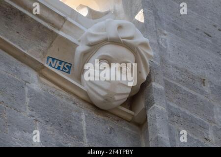 Sculpture d'un travailleur du NHS portant un masque sur le côté du Prieuré de Christchurch à Dorset pendant le troisième confinement national de l'Angleterre pour freiner la propagation du coronavirus. La sculpture est un hommage permanent aux efforts du service de santé pendant la pandémie et a été ajoutée au Prieuré - dont l'histoire remonte au milieu du XIe siècle - dans le cadre d'un projet visant à remplacer les gargouilles et les grottes endommagées. Date de la photo: Mardi 23 mars 2021. Banque D'Images