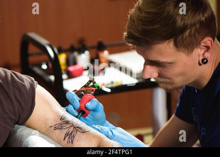 Tatoueur professionnel fait un tatouage sur la main d'un homme. Banque D'Images