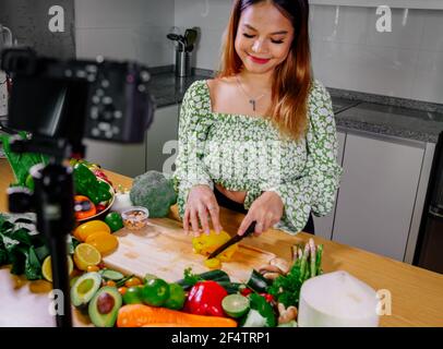 Femme asiatique blogueur ou créateur de contenu de cuisine et d'enregistrement caméra vidéo. Montrant la nourriture saine tout en enregistrant avec l'appareil photo dans la cuisine. Banque D'Images