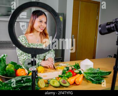 Femme asiatique blogueur ou créateur de contenu de cuisine et d'enregistrement caméra vidéo. Montrant la nourriture saine tout en enregistrant avec l'appareil photo dans la cuisine. Banque D'Images