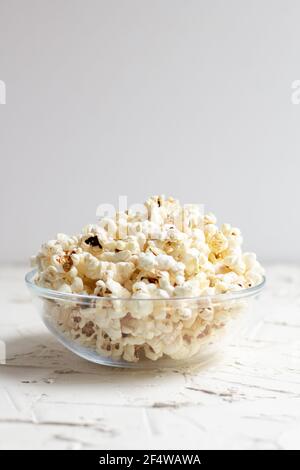 pop-corn dans un bol en verre transparent sur table blanche. CopySpace Banque D'Images