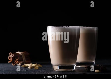 Deux tasses de thé Chai Latte, boisson chaude au thé avec lait mousse sur fond noir foncé Banque D'Images