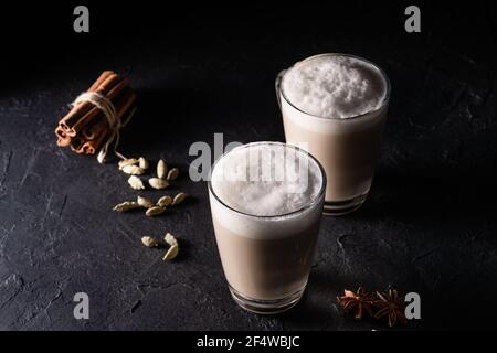 Deux tasses de thé Chai Latte, boisson chaude au thé avec lait mousse sur fond noir foncé Banque D'Images