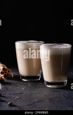 Deux tasses de thé Chai Latte, boisson chaude au thé avec lait mousse sur fond noir foncé Banque D'Images