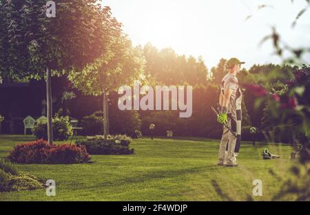 Caucasien Pro Gardener dans ses 40 s appréciant le moment dedans Ses clients jardin d'arrière-cour Banque D'Images