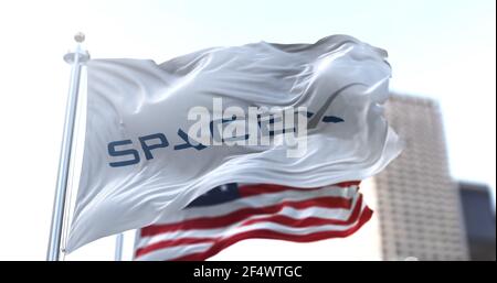 Hawthorne, CA, Etats-Unis, 9 mars 2021: Drapeau blanc avec le logo SpaceX qui flotte dans le vent avec les étoiles américaines et le drapeau à rayures en arrière-plan. A Banque D'Images