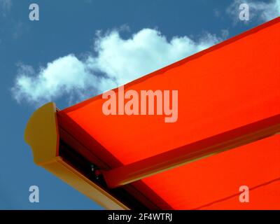 toile orange auvent sous ciel bleu clair. lumière du soleil jour d'été. concept de protection contre le soleil. Exposition aux UV. Matériau imperméable texturé brillant Banque D'Images