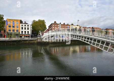 Paysage avec vue panoramique sur le pont Ha'penny un pont piétonnier en fonte et un point de repère historique local sur la rivière Liffey à Dublin, en Irlande. Banque D'Images