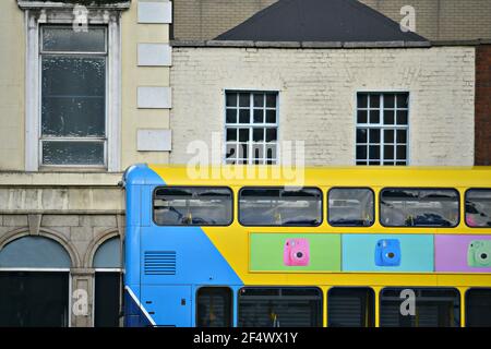 Façade vue sur un ancien bâtiment commercial avec un bus à impériale coloré au premier plan dans le centre-ville de Dublin, en Irlande. Banque D'Images