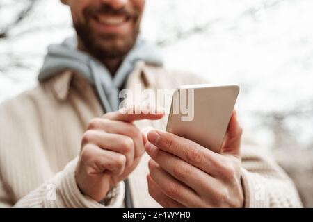vue rognée de l'homme barbu pointant du doigt vers le smartphone Banque D'Images