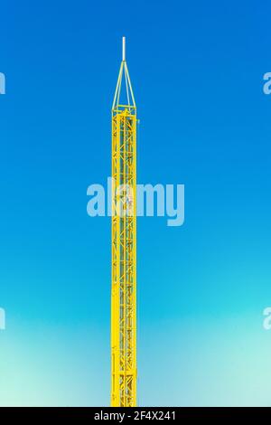 Attraction tour jaune dans un parc d'attractions sur fond bleu ciel. Banque D'Images