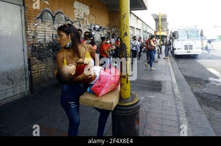 Valence, Carabobo, Venezuela. 23 mars 2021. 23 mars 2021.UNE femme allaite son enfant, devant un arrêt de transport en commun, tandis qu'un groupe de personnes se promit le long de la route publique où la plupart d'entre eux portent des masques comme mesure de prévention des covirus. Photo: Juan Carlos HernÃndez crédit: Juan Carlos Hernandez/ZUMA Wire/Alay Live News Banque D'Images