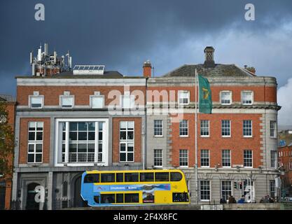 Façade vue sur un bâtiment commercial en brique avec un bus à impériale coloré au premier plan dans le centre-ville de Dublin, en Irlande. Banque D'Images