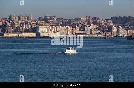 Un yacht à moteur naviguant dans la baie de Santander Cantabria Espagne avec la ville et le terminal de ferry derrière un matin de printemps calme et ensoleillé Banque D'Images