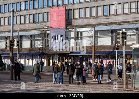 Personnes debout aux feux de signalisation par Mannerheimintie, le grand magasin Sokos en arrière-plan, à Helsinki, en Finlande. Banque D'Images