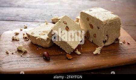 Tahini de sésame à la halva et amandes sur fond de table en bois. Morceaux de halvah ou de halwa à la vanille avec noix, gros plan, espace de copie. Dessert traditionnel confect Banque D'Images