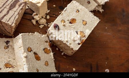 Tahini de sésame à la halva et amandes sur fond de table en bois. Morceaux de halvah ou de halwa à la vanille avec noix, gros plan, espace de copie. Dessert traditionnel confect Banque D'Images