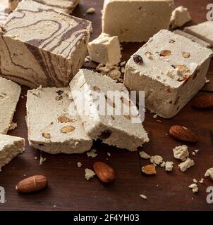 Cacao et amandes de la variété Halva sur fond de table en bois. Morceaux de halvah ou de halwa à la vanille avec noix, gros plan, confection de dessert traditionnelle faite avec de l'humour Banque D'Images