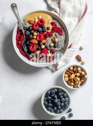 Bol pour le petit-déjeuner - bol au beurre d'arachide et à la gelée vegan chia fait de confiture de framboise maison, recouvert de fruits frais, de beurre d'arachide et de noix Banque D'Images