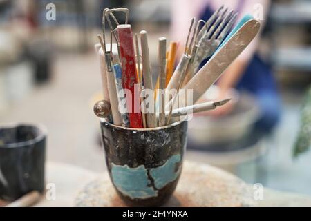 Poterie. Gros plan du pot avec des outils, des brosses pour la création de céramique d'argile faite à la main dans un atelier Banque D'Images