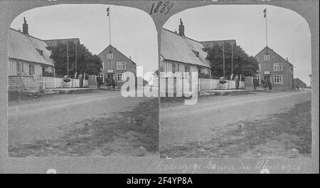 Akureyri (Islande). Hauptstraße (non pavée) avec des bâtiments résidentiels et commerciaux et le seul arbre du village (Ebersche) Banque D'Images