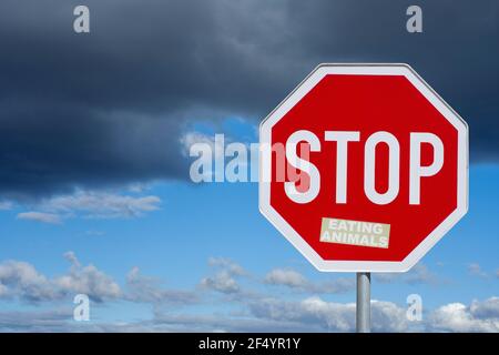 Panneau de signalisation, panneau stop avec autocollant „manger des animaux“, ciel avec des nuages sombres, image symbolique pour arrêter de manger des animaux, Banque D'Images