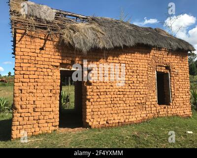 Une maison traditionnelle malgache de village en argile rouge avec un toit cassé Banque D'Images