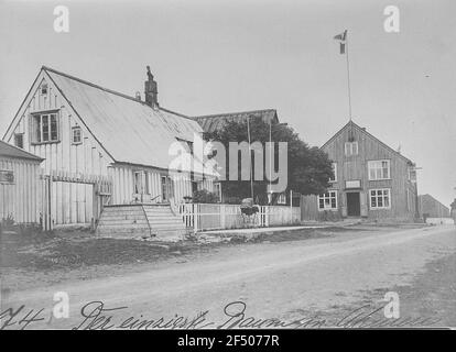 Akureyri (Islande). Hauptstraße (non pavée) avec des bâtiments résidentiels et commerciaux et le seul arbre du village (Ebersche) Banque D'Images