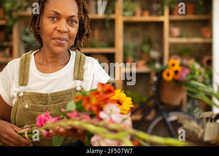 Portrait femelle fleuriste organisant des fleurs dans la boutique Banque D'Images