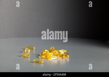 Capsules de gélatine transparente avec de l'huile de poisson sur une table grise. Compléments alimentaires, vitamines, Omega-3. Soins de santé, nutrition appropriée. Banque D'Images