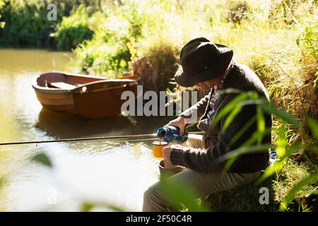 L'homme pêche à la mouche et le café versant à la rivière ensoleillée Banque D'Images