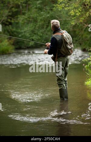 Homme avec sac à dos pêche à la mouche à la rivière Banque D'Images