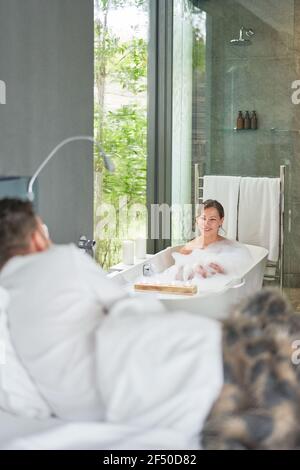 Couple prenant le bain et se coucher dans le lit dans le luxe moderne chambre d'hôtel Banque D'Images