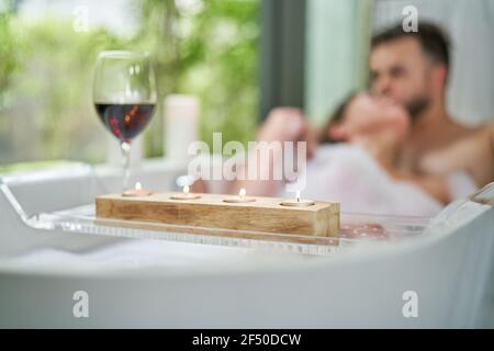 Couple romantique profitant d'un bain de bulles et du vin dans la baignoire Banque D'Images