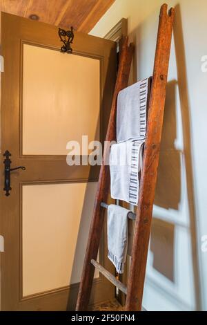 Porte-vêtements en bois antique à suspendre avec serviettes de bain derrière Porte dans la salle de bains principale à l'intérieur d'un vieux Canadiana vers 1735 maison en pierre de champ Banque D'Images