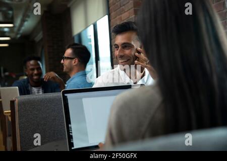 Homme d'affaires heureux parlant sur smartphone en réunion Banque D'Images