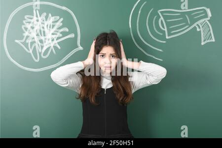 Une adolescente en colère et irritée ferme ses oreilles d'un mégaphone craché fort écrit à la commission scolaire. Photo haute résolution. Profondeur de champ complète. Banque D'Images