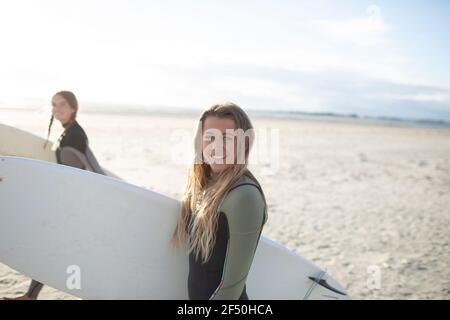 Portrait bonne jeune femme surfeuse avec planche de surf sur la plage ensoleillée Banque D'Images