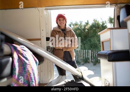 Portrait bonne jeune femme surfeuse dans la porte de camping-car ensoleillée Banque D'Images