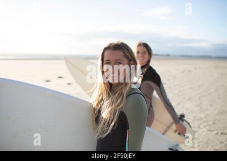 Portrait bonne jeune femme surfeuse avec planche de surf sur la plage ensoleillée Banque D'Images