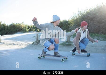 Jeunes femmes insouciantes, amis, skate sur la promenade de la plage Banque D'Images