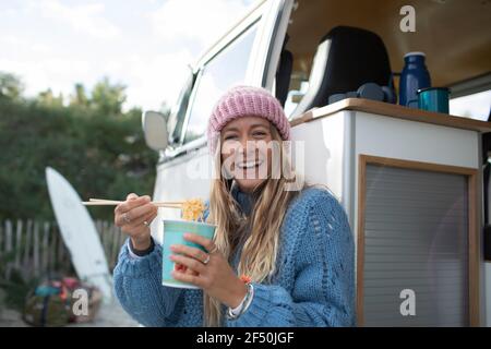 Portrait bonne jeune femme mangeant des nouilles instantanées au camping-car Banque D'Images