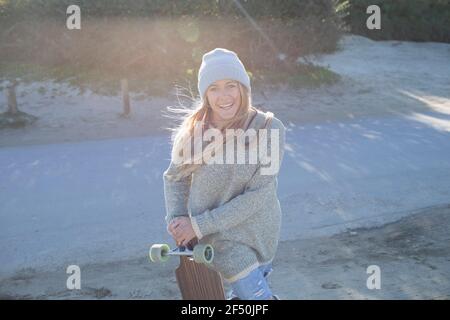 Portrait confiante jeune femme avec planche de surf sur la plage ensoleillée Banque D'Images